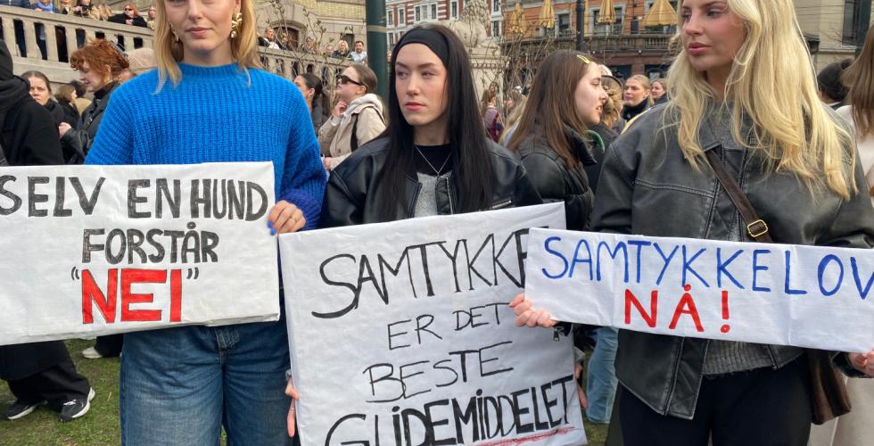 Tre jenter holder skilt p&aring; demonstrasjon for samtykkelov.