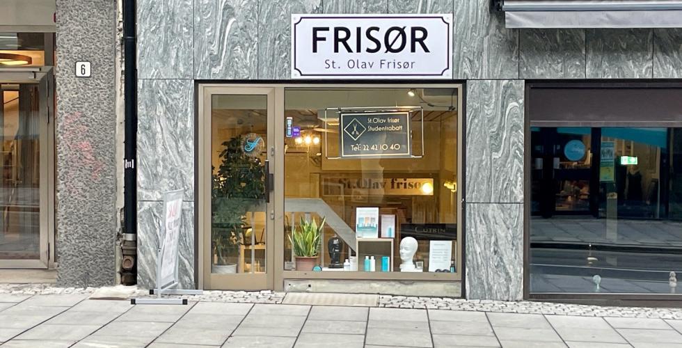 Bildet viser inngangen til St. Olav Fris&oslash;r i St. Olavs Gate i Oslo. I vinduet til salongen ser man planter, h&aring;rprodukter og et skilt med telefonnummeret til salongen og informasjon om studentrabatt.
