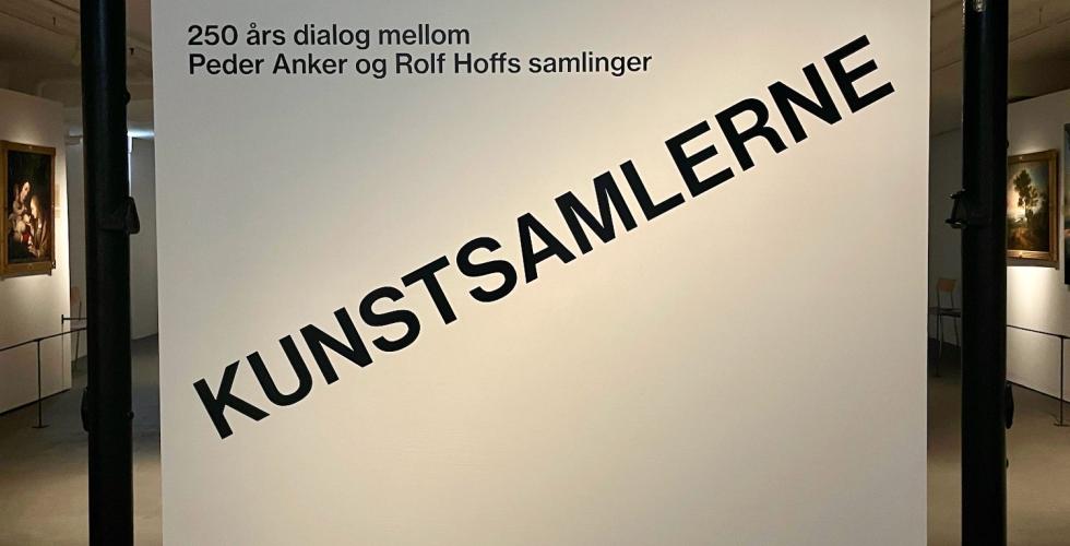 Bildet viser inngangspartiet til kunstutstillingen p&aring; Bogstad g&aring;rd. Den heter Kunstsamlerne, og navnet er skrevet i svarte blokkbokstaver p&aring; et hvitt lerret. 