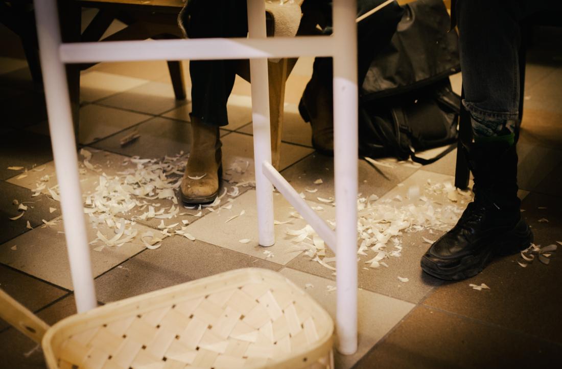 F&oslash;tter som sitter ved et bord med treverksrester rundt 