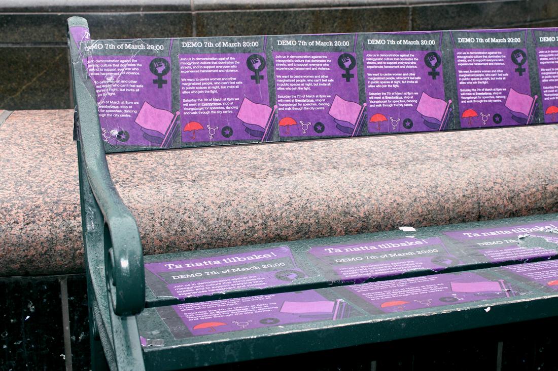 Benk med plakater der det står informasjon om 8. mars eventet