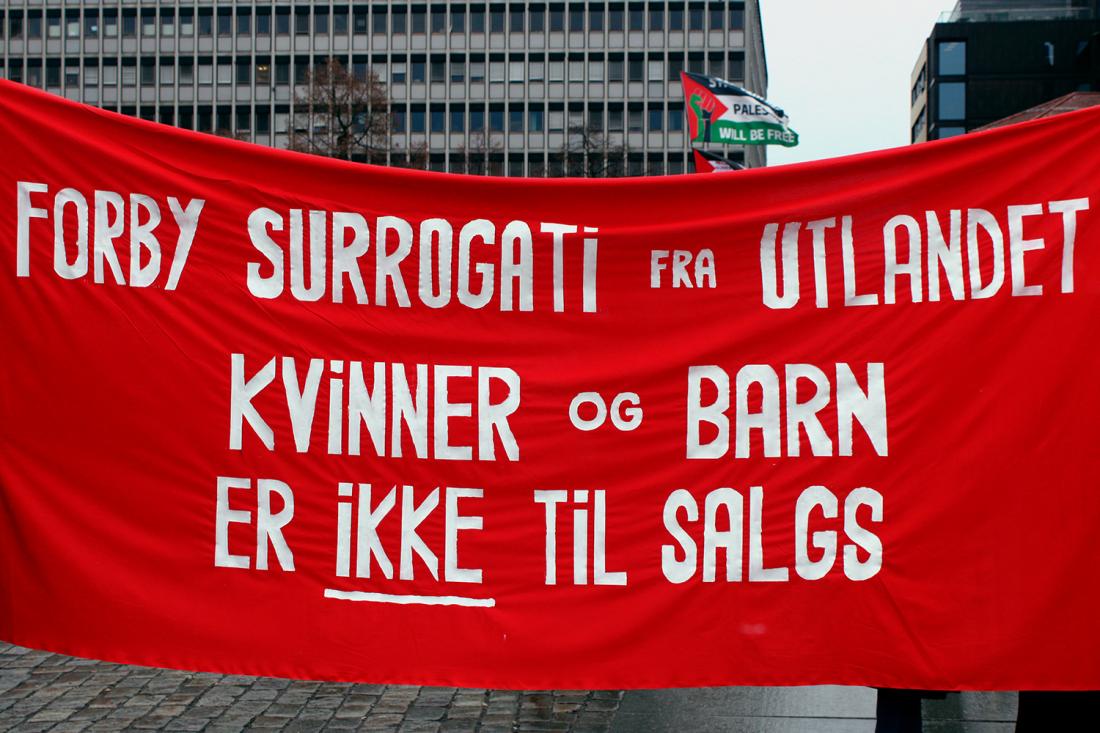 Banner der det står "forby surrogati fra utlandet, kvinner og barn er ikke til salgs"